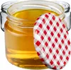 A close-up shot of a glass jar filled with honey, with a red and white checkered lid partially covering it. Other empty jars are visible in the background. Anteprima dell’immagine prodotto