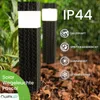 Two black solar garden lights with white tops are shown in a garden setting with rain falling. Náhled obrázku produktu