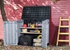 An outdoor storage shed filled with tools and supplies, placed against a red wooden wall. Náhled obrázku produktu