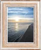 A framed picture of a beach at sunset. Produktbild-Vorschau