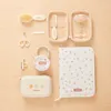 A flat lay of a baby care kit laid out on a wooden surface. Produktbild-Vorschau