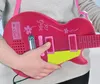 A person is holding a pink toy guitar. Voir les images du produit