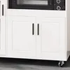 A close-up view of the lower cabinet doors and a microwave oven on top of a white sideboard. Anteprima dell’immagine prodotto