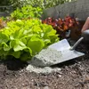 A close-up shot of a garden bed with lettuce plants and a trowel filled with soil amendment. Produktbild-Vorschau