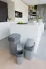 A modern kitchen with three grey trash bins in the foreground. Voir les images du produit
