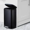 A black trash can with its lid open, placed next to a white cabinet. Produktbild-Vorschau