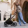 A woman pushing a baby stroller down a cobblestone street. Voir les images du produit