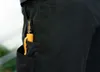 A close-up shot of a black marker with an orange clip and gold accents, tucked into the pocket of black pants. Produktbild-Vorschau