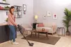A woman is vacuuming a living room with a Hoover vacuum cleaner. Voir les images du produit