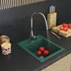 A kitchen sink with a faucet running water into it, with tomatoes and a knife on a cutting board nearby. Anteprima dell’immagine prodotto
