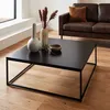 A modern living room scene with a black metal coffee table in the foreground, featuring decorative items. A brown leather sofa is visible in the background. Anteprima dell’immagine prodotto