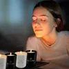 A young woman with her eyes closed is smelling scented candles. Produktbild-Vorschau