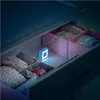 A drawer with organized clothing and a small blue night light. Voir les images du produit