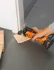 A person is using an oscillating multi-tool to cut a piece of wood flooring next to a doorway. Náhľad obrázku produktu