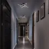 A modern hallway with dark doors, framed pictures on the wall, and two contemporary ceiling lights illuminating the space. Produktbild-Vorschau