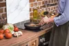 A person is cooking in a kitchen, with vegetables and cooking utensils visible on the counter. Anteprima dell’immagine prodotto