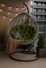 A hanging chair with a green cushion and a brown blanket on a balcony. Voir les images du produit