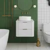A modern bathroom with green tiled walls and white tiled floor, featuring a white bathtub, a white vanity with a vessel sink, and a toilet. Produktbild-Vorschau