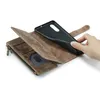 A hand is shown placing a black phone case into a brown leather wallet case with card slots and a zipper. Produktbild-Vorschau