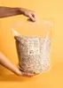 Hands holding a large bag of oats. Produktbild-Vorschau