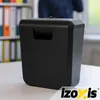 A black paper shredder sits on a white desk in an office setting. Produktbild-Vorschau