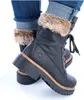 A close-up shot of a pair of black lace-up boots with fur trim, worn with cuffed jeans. Anteprima dell’immagine prodotto