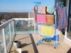 A clothes drying rack on a balcony with a city view. Produktbild-Vorschau