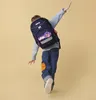 A child wearing a backpack is shown from behind, in motion against a plain background. Anteprima dell’immagine prodotto