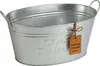 A silver-colored oval metal tub with handles, designed for chilling drinks, sits on a white background. A small brown leather tag with German text is attached to the side. Voir les images du produit