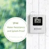 A weather station is shown mounted on a wall with water droplets, suggesting its water-resistant features. The background shows rain and a textured wall. Produktbild-Vorschau