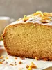 A close-up of a slice of cake with orange zest and powdered sugar on top. Produktbild-Vorschau