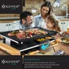 A family is enjoying a raclette grill meal in a kitchen setting. Produktbild-Vorschau
