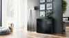 A modern living room with a black sideboard, a floor lamp, and artwork on the wall. Produktbild-Vorschau
