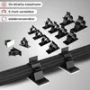 A collection of black cable clips are displayed on a gray background, with a black cable running across the foreground, held by some of the clips. Produktbild-Vorschau
