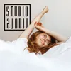 A woman with red hair is stretching in bed, covered by white sheets. Produktbild-Vorschau