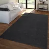 A dark gray rug is placed on a wooden floor in front of a white sofa in a living room. Produktbild-Vorschau