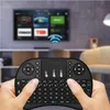 Hands holding a black wireless keyboard with a touchpad in front of a blurred television screen. Anteprima dell’immagine prodotto
