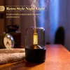 A retro-style aroma diffuser with a warm white light is shown on a wooden table, emitting mist. Podgląd zdjęcia produktu