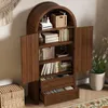 A wooden cabinet with open doors, displaying shelves filled with books and decorative items. A woven basket and a plant are also visible. Anteprima dell’immagine prodotto