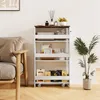 A white rolling storage cart with four shelves is placed next to a sofa and a potted plant. Podgląd zdjęcia produktu