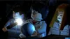 Three Lego characters in a dark, possibly magical setting. One character on the left is holding a wand that is emitting light. The character in the middle is holding a glowing orb. The character on the right looks concerned. Produktbild-Vorschau
