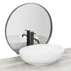A white oval basin sink with black faucets is shown in front of a round mirror on a wooden surface. Náhled obrázku produktu