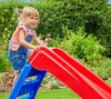 A young girl is playing on a slide in a garden. Anteprima dell’immagine prodotto