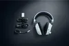 A pair of white and black gaming headphones with accessories laid out on a dark background. Produktbild-Vorschau