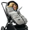 A baby is sitting in a stroller, wrapped in a gray sleeping bag with a fur-lined hood. Podgląd zdjęcia produktu