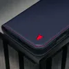 A close-up shot of a dark blue leather phone case with red stitching and a red bull logo. Anteprima dell’immagine prodotto