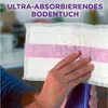 A hand holding a Swiffer Wetjet floor wipe with a purple stripe, with a blurred kitchen background. Anteprima dell’immagine prodotto