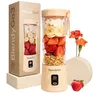 A product shot of a portable blender with ingredients and packaging, along with decorative flowers and a strawberry. Podgląd zdjęcia produktu