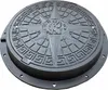 A black manhole cover with a compass rose design. Produktbild-Vorschau