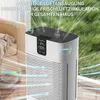 An air purifier is shown in a living room setting with a couch and a window overlooking a grassy area. The air purifier is actively circulating air, indicated by visual effects. Produktbild-Vorschau